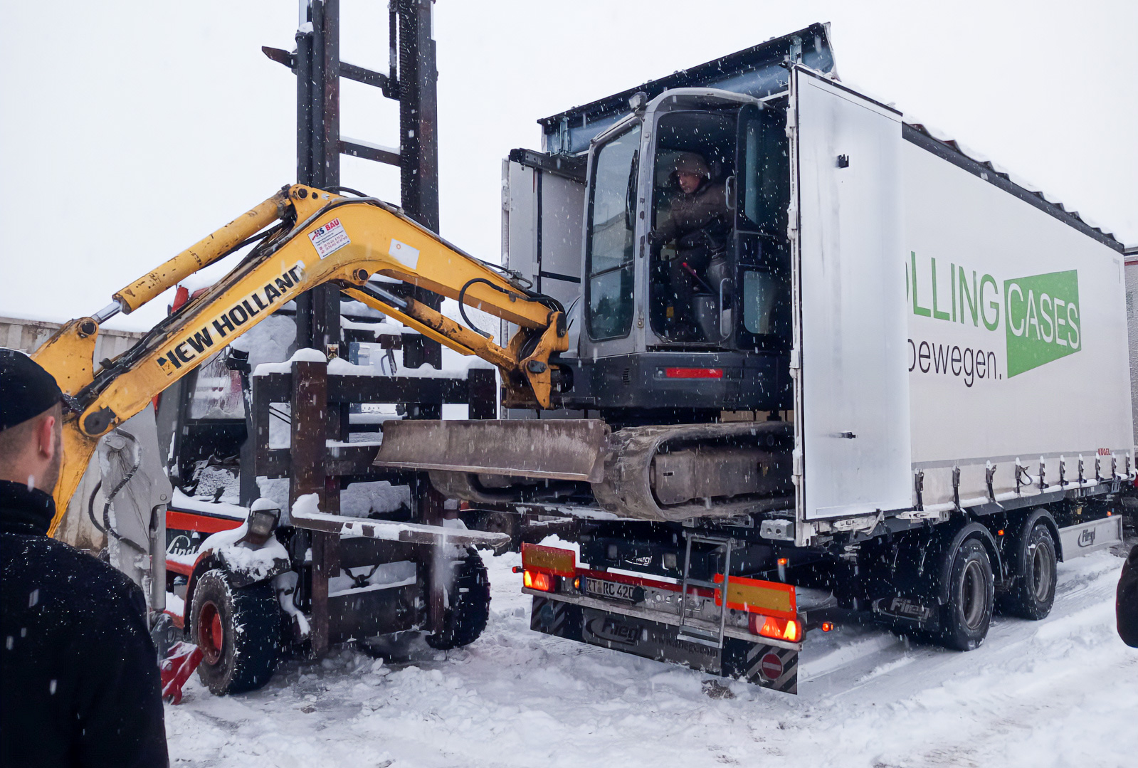 LKW der Rolling Cases GmbH beladen mit einem Bagger im Schneegestöber